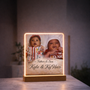 Personalized illuminated LED photo frame featuring two baby photos, custom names and a wooden display base
